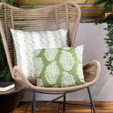 Kalindi reversible polyester cushions in olive, showing paisley print in white-on-olive and olive-on-white, styled on a woven rattan chair.