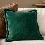 Kallu Plain Faux Fur Cushion in needle green, square with a raised border and plush pile, shown on a sofa beside a brown textured cushion.