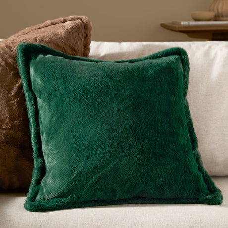 Kallu Plain Faux Fur Cushion in needle green, square with a raised border and plush pile, shown on a sofa beside a brown textured cushion.
