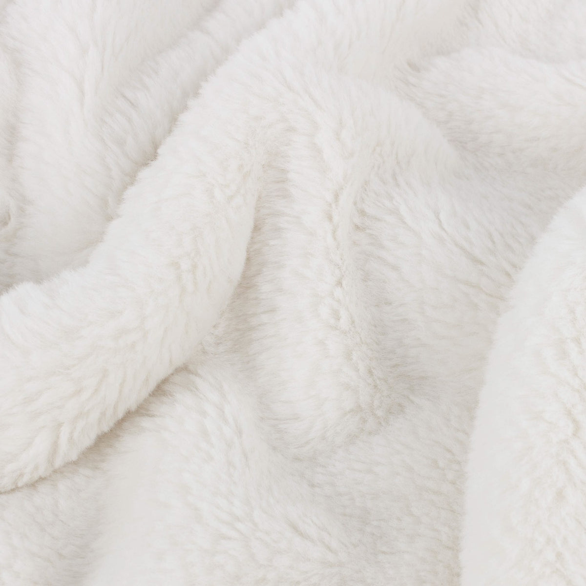 Close-up of the Kallu Reversible Faux Fur Throw in ecru, showing soft, dense pile fabric with gentle folds in a plain neutral tone.