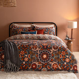 Kinfolk Reversible Floral Duvet Cover Set in Denim Blue with rust, orange and cream medallion print, styled on a bed with matching pillowcases in a warm-toned bedroom.