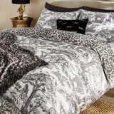 Kisumu Cotton Jungle Duvet Cover Set in monochrome, styled on a bed with matching pillowcases, a leopard-print throw, and a black cushion with tiger motifs in a bedroom setting.