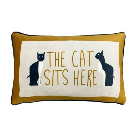 Ochre velvet lumbar cushion with cream centre panel, navy piping, and two black-and-white cats flanking The Cat Sits Here text, shown on a white background.