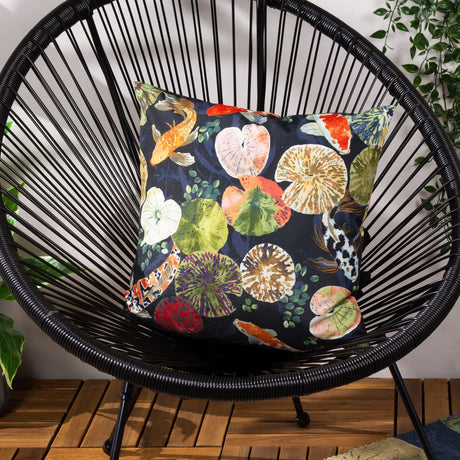 Koi Pond Reversible Polyester Cushion in Midnight, square scatter cushion with koi carp and lily pad print on black woven wicker chair.