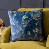 Navy velvet Koi Pond cushion with gold embroidered koi carp design, shown on a mustard yellow armchair in a living room setting.