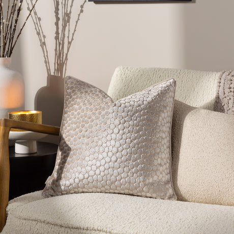 Lanzo Abstract Velvet Cushion in Moonbeam, a 45 x 45cm square cushion with cut-velvet circular pattern in cream and silver tones, shown on a cream boucle armchair.