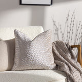 Lanzo Abstract Velvet Cushion in Moonbeam, a cream-toned square cushion with a dotted cut-velvet texture, shown on a cream boucle sofa beside a woven throw.