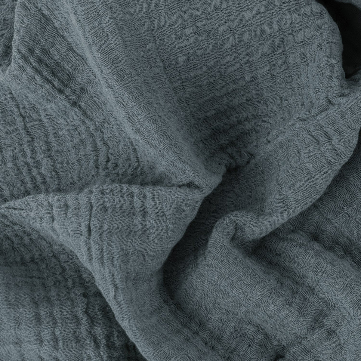 Close-up of the Lark Plain Cotton Throw in dusk blue, showing the crinkled, textured surface created by four layers of cotton muslin.