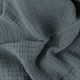 Close-up of the Lark Plain Cotton Throw in dusk blue, showing the crinkled, textured surface created by four layers of cotton muslin.