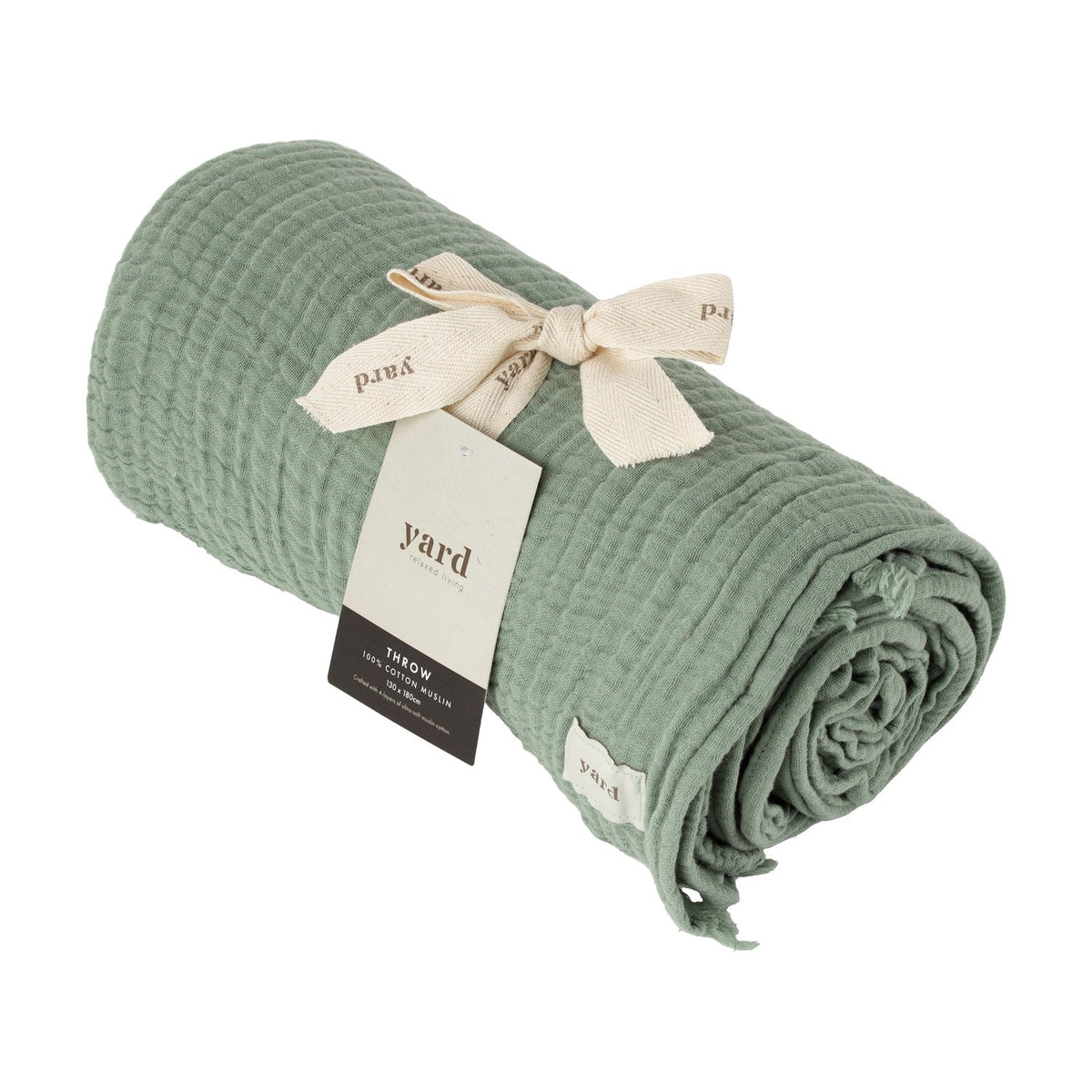 Lark Plain Cotton Throw in eucalyptus green, rolled with a crinkled muslin texture, tied with a cream ribbon and branded Yard tag, on a white background.