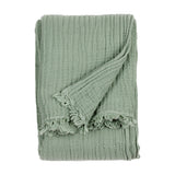 Lark Plain Cotton Throw in eucalyptus green, folded to show its crinkled cotton muslin texture and frayed edge, on a plain white background.