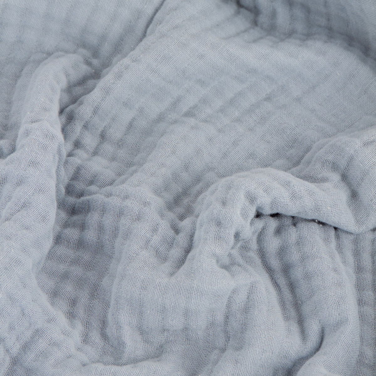 Lark Plain Cotton Throw in mineral blue, showing the layered muslin fabric's crinkled texture in a close-up view.