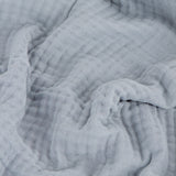 Lark Plain Cotton Throw in mineral blue, showing the layered muslin fabric's crinkled texture in a close-up view.