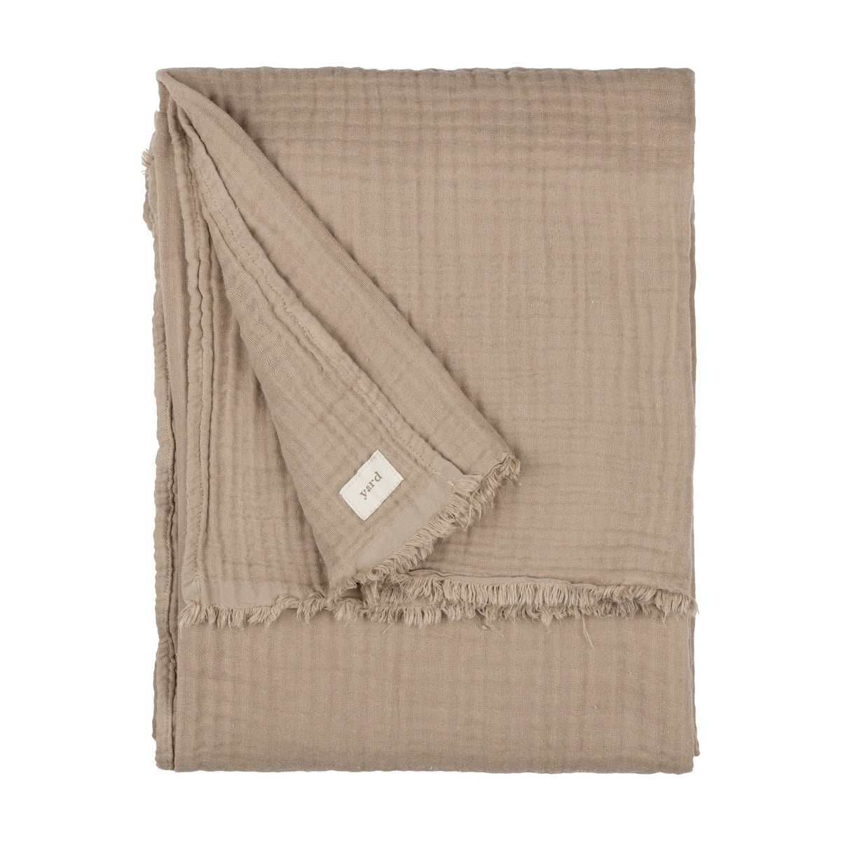 Lark Plain Cotton Throw in mole, a folded four-layer cotton muslin throw with a fringed edge and fabric brand tag, shown on a plain white background.