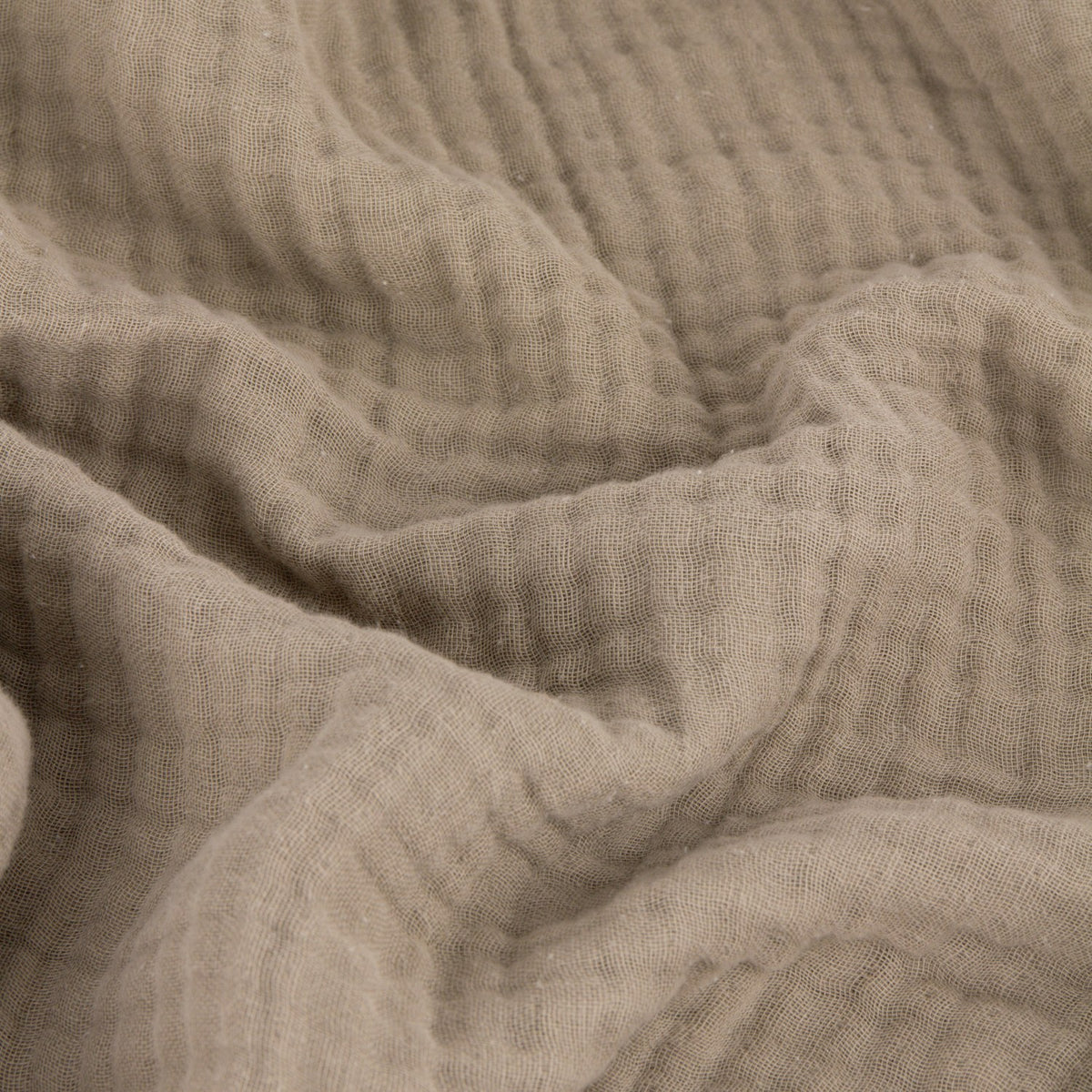 Close-up of the Lark Plain Cotton Throw in mole, showing the crinkled texture and ridges of layered cotton muslin fabric in a soft grey-taupe brown.
