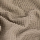 Close-up of the Lark Plain Cotton Throw in mole, showing the crinkled texture and ridges of layered cotton muslin fabric in a soft grey-taupe brown.