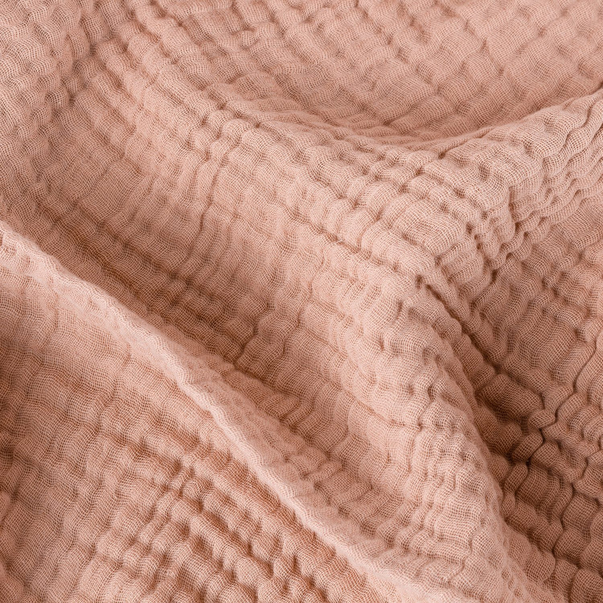 Close-up of the Lark Plain Cotton Throw in pink clay, showing the crinkled, layered muslin cotton texture in a soft dusty pink tone.