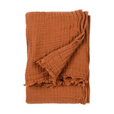 Lark Plain Cotton Throw in pecan, folded to show its crinkled muslin texture and frayed raw edge, against a plain white background.