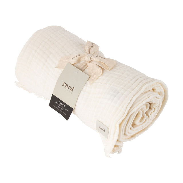 Lark Plain Cotton Throw in white, rolled and tied with a ribbon and branded tag, showing crinkled muslin texture and a frayed edge, on a plain white background.