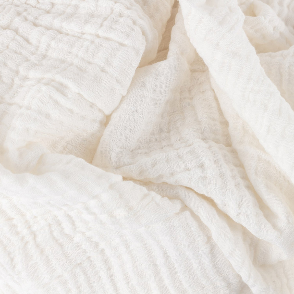 Close-up of the Lark Plain Cotton Throw in white, showing crinkled four-layer muslin cotton fabric with soft folds and natural woven texture.