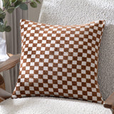 Larro Jacquard Chenille Cushion in Copper, a square cushion with a woven rust-brown and oatmeal checkerboard pattern, shown on a textured armchair.