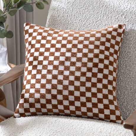 Larro Jacquard Chenille Cushion in Copper, a square cushion with a woven rust-brown and oatmeal checkerboard pattern, shown on a textured armchair.
