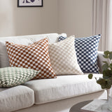 Larro Jacquard Chenille Cushion in Smoke Green with a checkerboard pattern woven in chenille, styled on a beige sofa alongside terracotta, cream, and navy checked cushions.