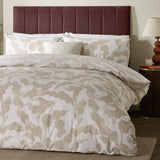 Lauro Reversible Leaf Duvet Cover Set in stone, styled on a bed with matching pillowcases in a bedroom with a burgundy upholstered headboard.