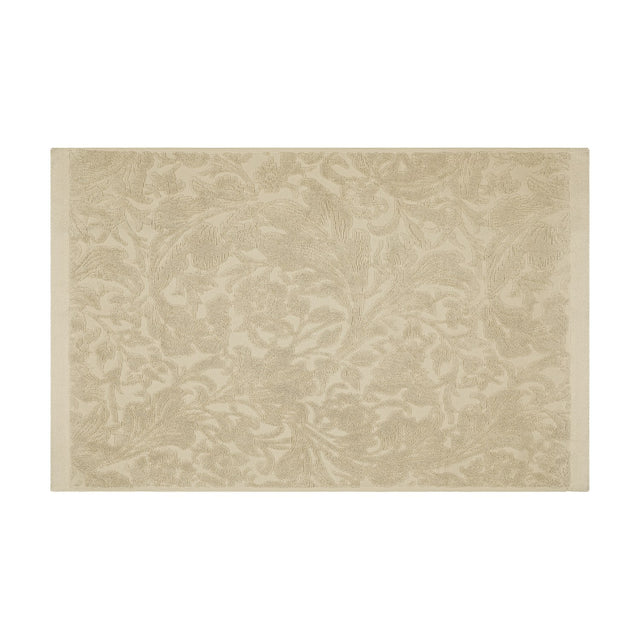 Leicester Floral Cotton Bath Mat in natural, rectangular with woven tone-on-tone scrollwork pattern and plain border edging, shown on a plain white background.