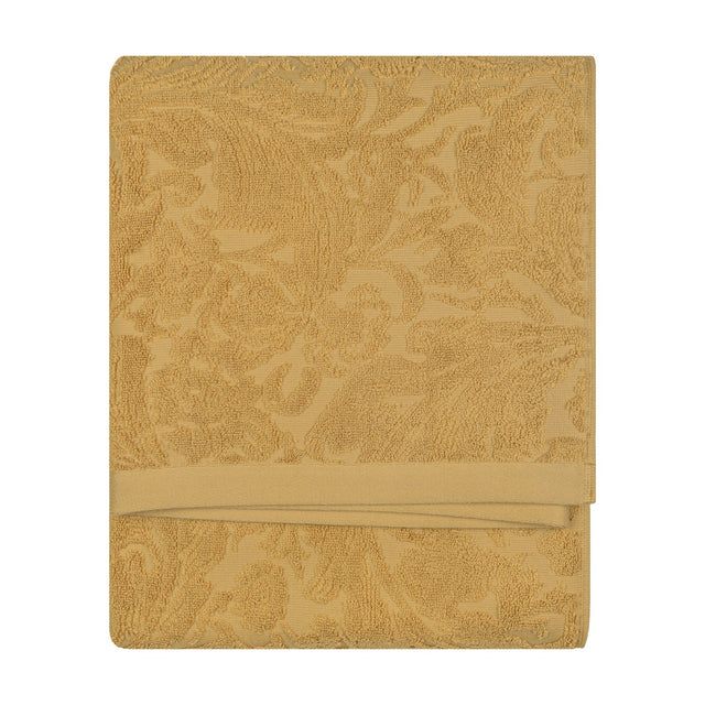 Folded Leicester cotton towel in gold with a sculptured floral and foliage pattern, woven border, shown against a plain white background.