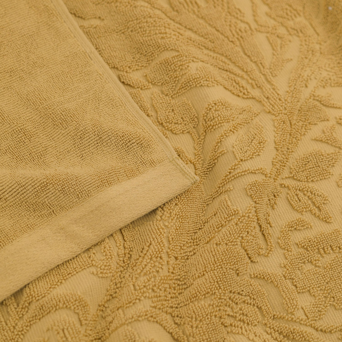 Leicester Floral Cotton Towels in gold, close-up of the folded edge and sculpted heritage foliage pattern in soft honey-toned pure cotton pile.