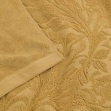 Leicester Floral Cotton Towels in gold, close-up of the folded edge and sculpted heritage foliage pattern in soft honey-toned pure cotton pile.