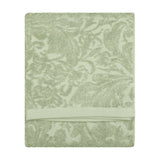 Folded Leicester cotton towel in sage green with a woven floral and foliage jacquard pattern and plain woven border band, shown on a white background.