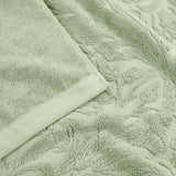 Close-up of Leicester Floral Cotton Towels in sage green, showing a raised leaf and foliage pattern woven into the cotton pile with a plain woven border edge.