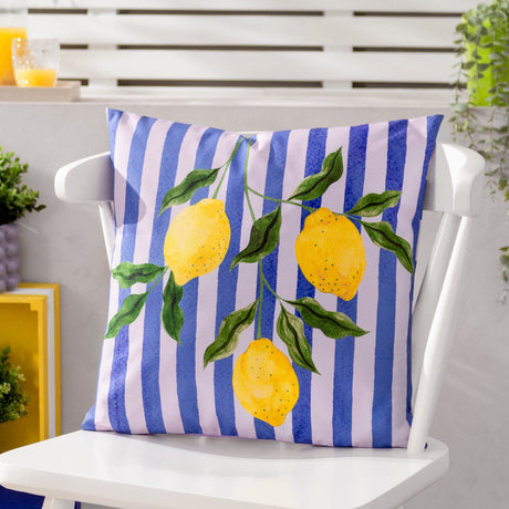 Square polyester outdoor cushion with blue and pale lilac vertical stripes, printed with yellow lemons on a leafy branch, shown on a white outdoor chair.
