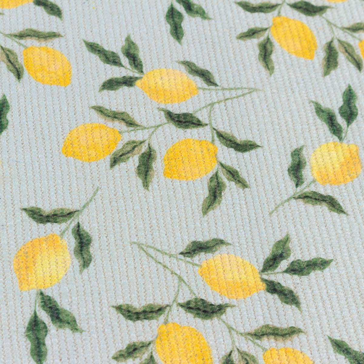 Close-up of the Lemons Floral Table Runner in blue, showing digitally printed yellow lemons and green leaves on a ribbed woven polyester fabric.