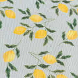 Close-up of the Lemons Floral Table Runner in blue, showing digitally printed yellow lemons and green leaves on a ribbed woven polyester fabric.