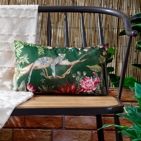 Rectangular Leopard Jungle polyester cushion in forest green, featuring a leopard on a branch amid florals, displayed on a black chair against a bamboo backdrop.
