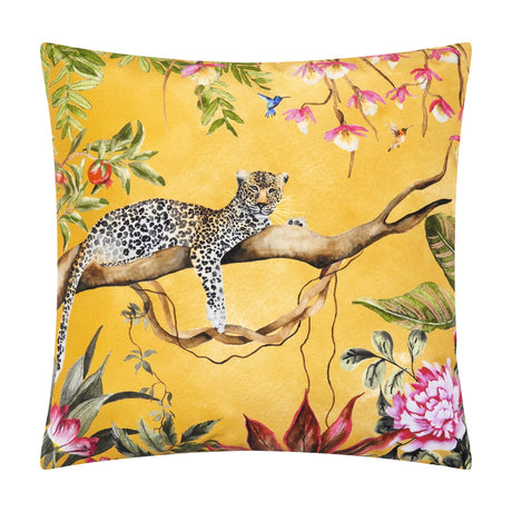 Square gold polyester cushion featuring a hand-painted leopard resting on a branch amid tropical foliage, orchids, peonies and hummingbirds, shown on a white background.