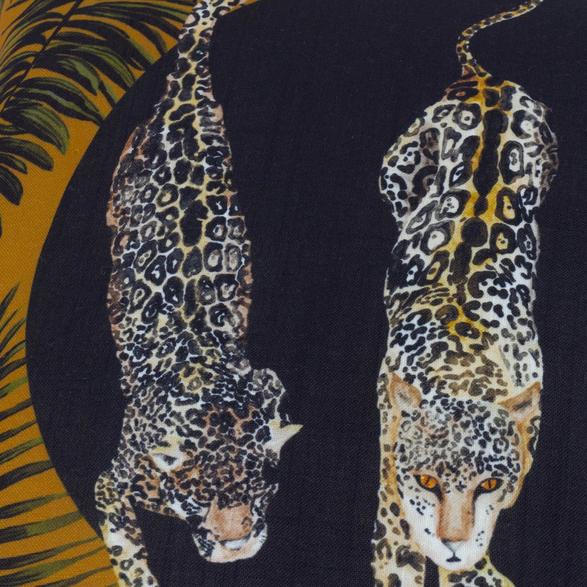 Leopardis reversible polyester cushion, close-up of two prowling leopards printed in black and gold on a dark background with amber palm fronds at the edge.