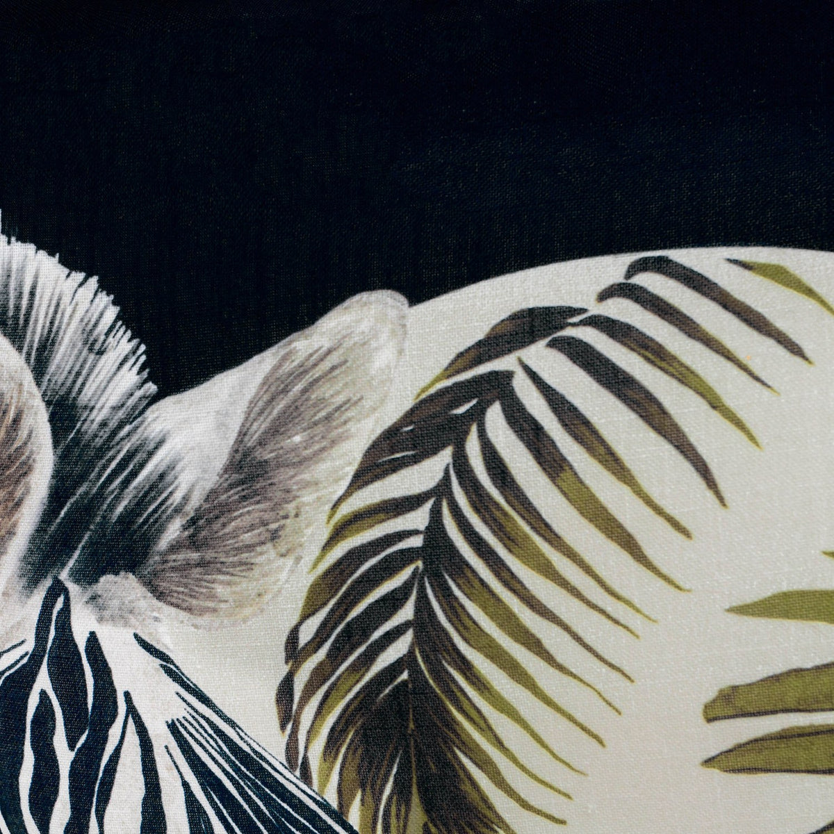 Leopardis reversible polyester cushion close-up showing a zebra head with olive and cream palm frond print on a black ground.