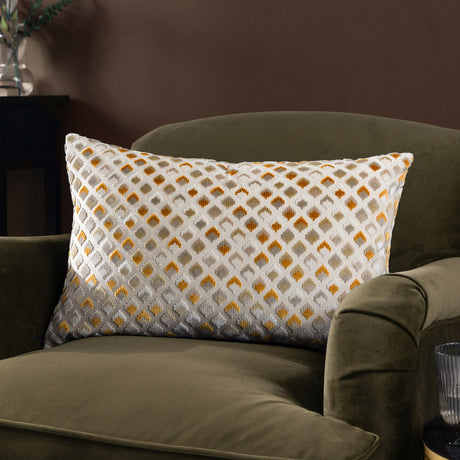 Lexington Jacquard Velvet Cushion in gold on an olive velvet armchair, rectangular with a diamond lattice pattern in gold, ochre, grey and taupe on a cream base.