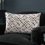 Lexington Jacquard Velvet Cushion in Grey/Black, a rectangular bolster with diamond-patterned woven velvet face, shown on a black velvet armchair in a dark-toned room.