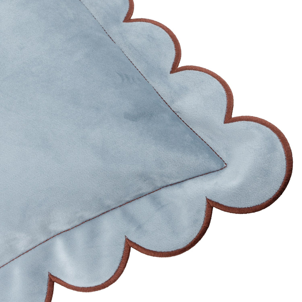 Close-up of the Lil Scallop Plain Velvet Cushion in blue, showing its velvet fabric corner with a scalloped edge and contrasting brown trim on a white background.