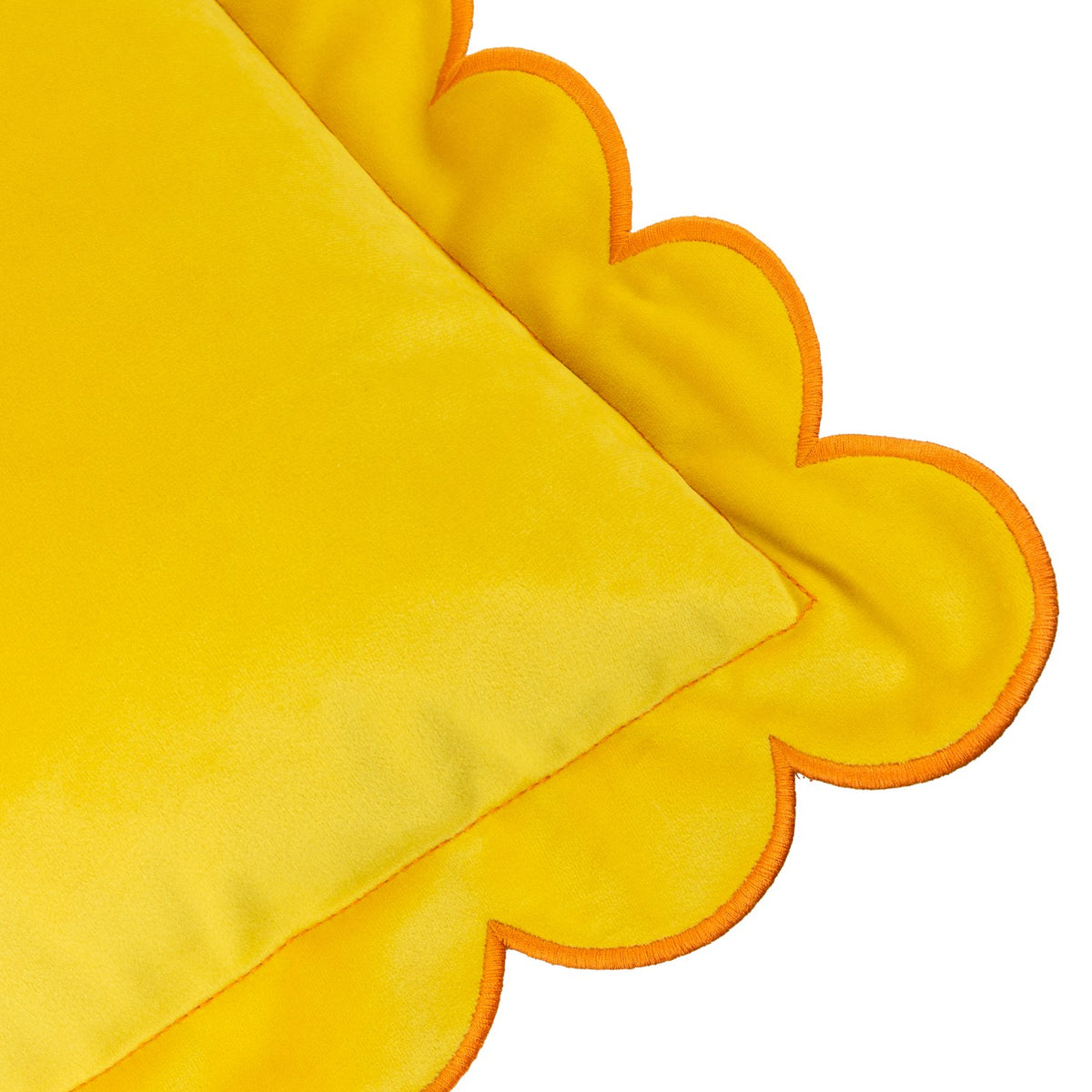 Close-up of the Lil Scallop Plain Velvet Cushion in lemon yellow velvet with a wavy scalloped edge trimmed in ginger orange, shown on a plain white background.