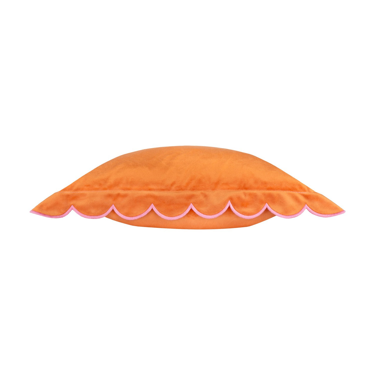 Side view of the Lil Scallop velvet cushion in orange, showing its scalloped edge trim in contrast pink thread, on a plain white background.