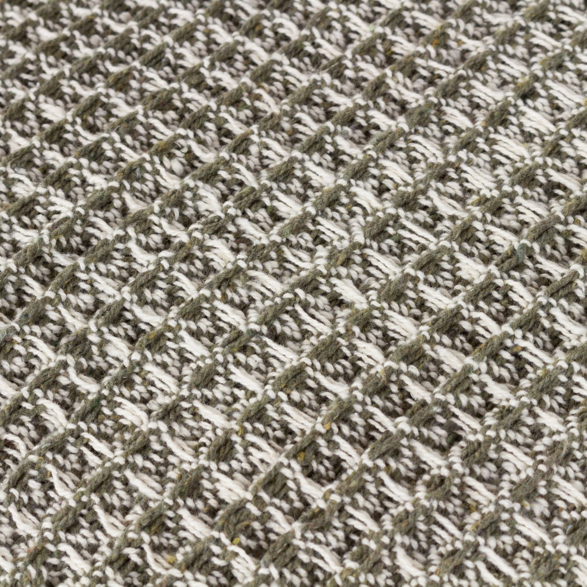 Close-up of the Lorne Plain Cotton Throw in Lichen, showing a chunky two-tone cotton waffle weave in muted green and white creating a textured, heathered surface.
