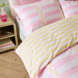 Lottie reversible duvet cover set shown on a bed with yellow and white striped disc-pattern duvet and matching pink striped pillowcases in a bedroom setting.