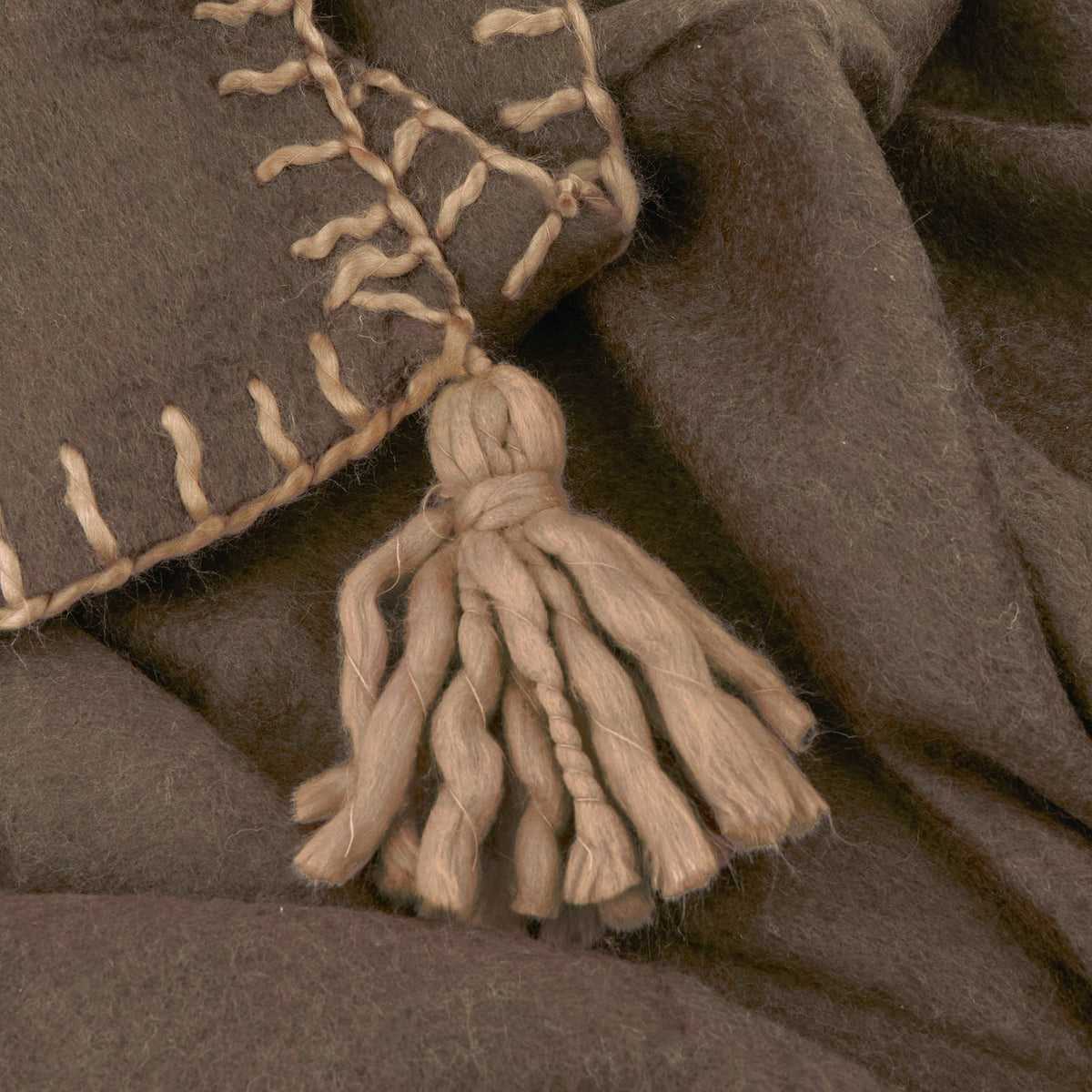 Close-up of the Lowen wool blend throw in chocolate brown, showing whipstitch edge detailing and a hand-tied tassel corner.