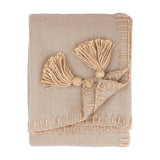 Lowen Wool Plain Polyester Throw in natural beige, folded, with hand-worked blanket-stitch edging and jumbo corner tassels, shown on a plain white background.